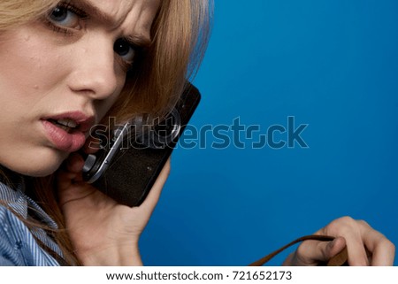 serious woman talking on the phone on a blue background                               