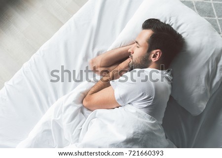 Cute young man sleeping on bed Royalty-Free Stock Photo #721660393