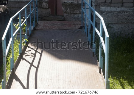 Blue ramp railing, rug and green yard. Summer texture