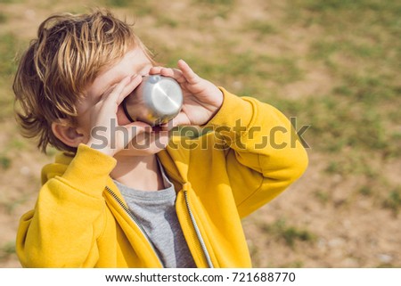 Portrait of Adorable cute boy resting and drinking tea from a thermos in the beauty autumn park.