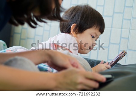 asian  chinese children playing tablet with mother on bed 

