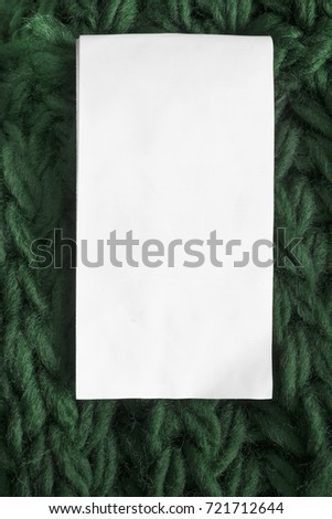 Blank white clothes label on dark green knitted background