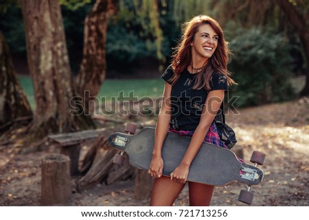 Portrait of a beautiful young woman holding a skateboard.