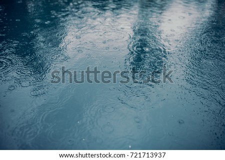 Water surface during rain. Rain drops are falling into the water.