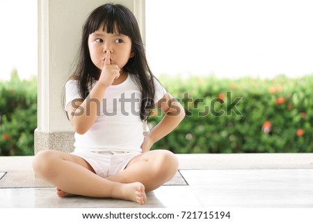 Asian children cute or kid girl squat and forefinger close mouth for tell quietly and secret surprise with play hide and seek at back pole with space Royalty-Free Stock Photo #721715194