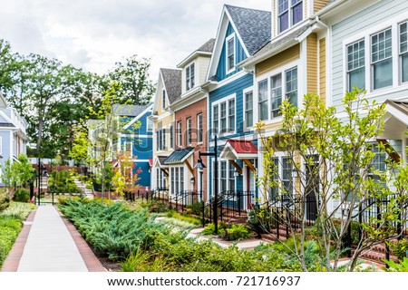 Row of colorful, red, yellow, blue, white, green painted residential townhouses, homes, houses with brick patio gardens in summer Royalty-Free Stock Photo #721716937