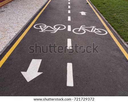 White bicycle sign with arrow on the asphalt, bike road sign on the street, bicycle lane sign on street, gray background Royalty-Free Stock Photo #721729372