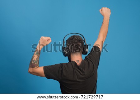 Relax and music concept. Dj with scorpio tattoo wears headphones. Singer enjoys music partying, copy space. Man holds hands up dancing on blue background.