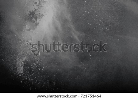 Freeze motion of white particles on black background. Powder explosion. Abstract dust overlay texture.       