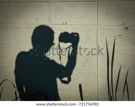 Soft blurred shadow of photographer take a photo on white brick wall and grass on sunset 