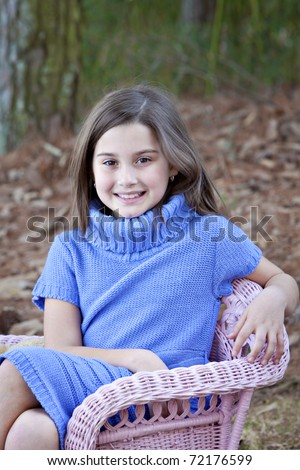 Beautiful little eight year old girl outdoors in beautiful blue sweater dress with cowl collar