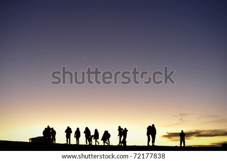Silhouette of people and photographers on mountain at dawn. Silhouettes of people against the night sky. After a decline.