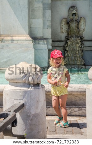 Little charming girl in a baseball cap on the Aqua Paola fountain in Rome, Italy