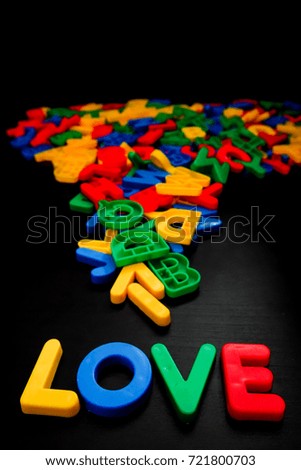Colorul plastic letters spelling text LOVE with colorful wooden shape on black background