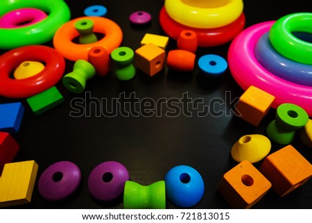 Border of colorful plastic letters , loop and wooden shape  with copy-space on black background.