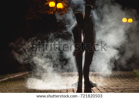The man and woman stand on the smoky alley. night time