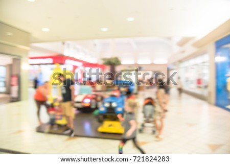 Blurred image kids enjoy riding electric toy cars in shopping mall, Houston, Texas, USA. Indoor game colorful electric powered sit on rides for infants, toddlers amusement park alike. Parent and child