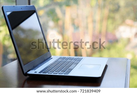 Laptop on wooden table near by window