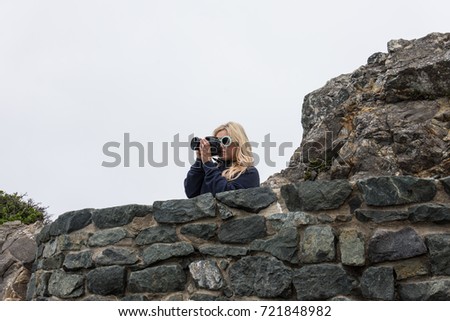Blonde adult woman in Patrick's Point State Park taking photos with a DSLR camera in Northern California