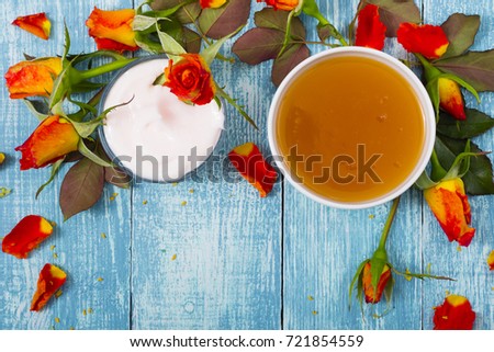 cosmetic creams and rose flowers on old blue wood table background