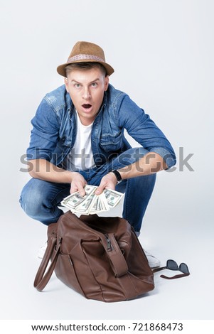 young happy man in a hat found money in a leather bag. man with dollar bills