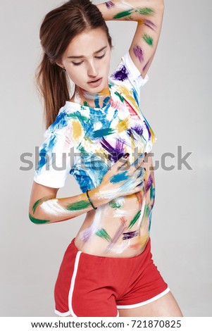 beautiful young woman is dirty in multicolored paint.