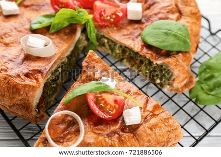 Tasty pie with spinach on metal grid, close up