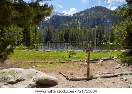 Lonely mountain in the rocky mountains with lake and wooden trail sign
