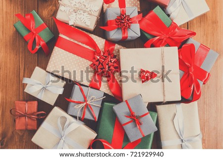 Lots of Gift boxes on wood background top view, flat lay. Presents in craft and colored paper decorated with red ribbon bows and snowflakes. Christmas and other holidays concept, copy space