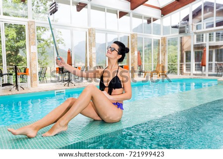 girl with sunglasses doing selfie in the pool at luxury hotel