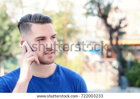 Portrait of young latin man talking on the phone against brick wall. Outdoors.
