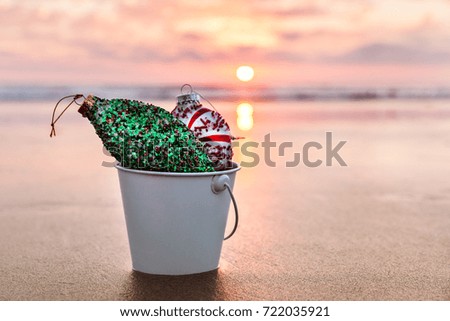 Christmas decorations collected in a white bucket on the beach at sunset time, holiday concept