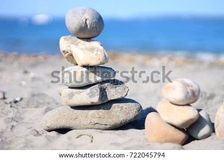 A small man-made pile of rocks on the beach. Their are two stacks. On the sand with the ocean and sky in the background. 