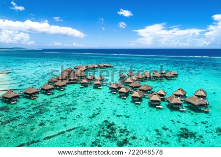 Beach travel vacation Tahiti hotel overwater bungalows luxury resort in coral reef lagoon ocean. Moorea, French Polynesia, Tahiti, South Pacific Ocean. Royalty-Free Stock Photo #722048578