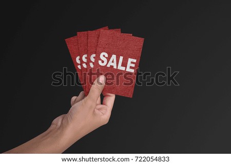 Hand holding a red card with text SALE in the black friday holiday