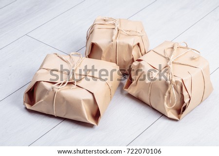 Gifts packed in craft paper package tied a rope on a white oak desk floor.