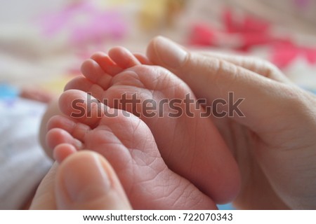 the legs of the baby in the hands of the mother and father