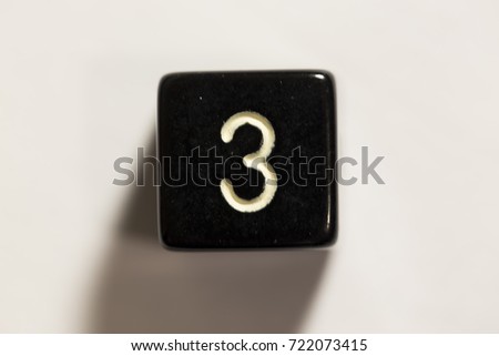 A black six-sided die with the number 3 showing.