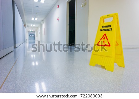 caution wet floor warning sign with blurred worker mopping floor.