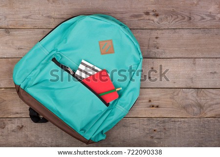 Backpack and school supplies: notepad, pencil on brown wooden table Royalty-Free Stock Photo #722090338