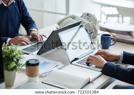 Cropped image of business people working on laptops in office