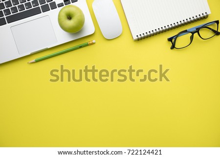 Modern yellow office desk table with laptop and blank notebook page for input the text. Top view, flat lay
