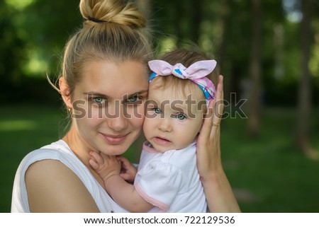 Beautiful young mother and her daughter in the park on a sunny autumn day - happy together portrait child, family concept.