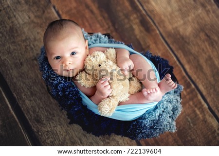 Little newborn baby boy, looking curiously at camera, posed picture
