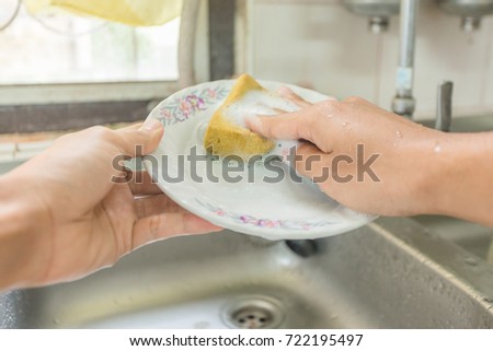 man hand washing dishes with sponge