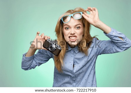 emotion on the face of a woman with glasses and camera in hand on a green background                               