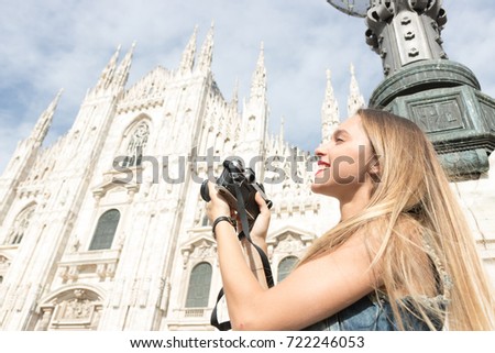 Pretty millennial teenager tourist outdoors in the city with a vintage reflex camera. Photo taken in Milan, Italy.