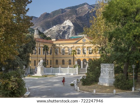 A lonely woman walks in the park of the library Biblioteca Civica Cesare Vico Lodovici, Carrara, Italy, with the mountains and the famous marble quarries in the background