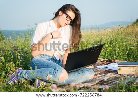 Young woman on grass with open laptop in a sunny day relaxing