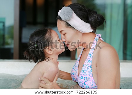 Cute little child girl and her mother in hot tub.